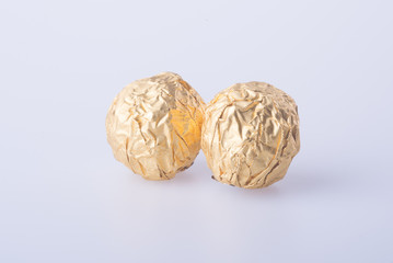 Fototapeta premium Chocolate ball in a gold foil paper on a background.