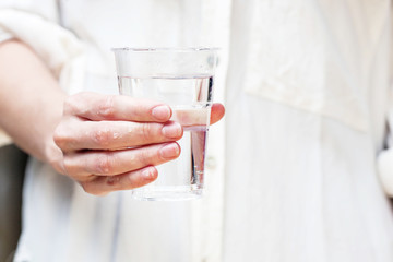 A glass of clean mineral water in woman's hands. Concept of environment protection, healthy lifestyle