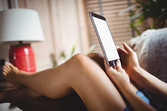 Woman using digital tablet in living room