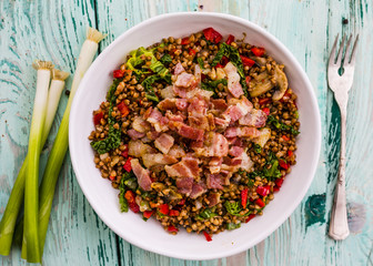 Buckwheat with bacon and vegetables served on white plate.