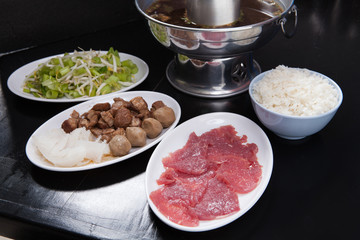 Dipping beef and stewed beef and rice with silver pot on black t