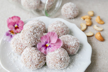 Fototapeta na wymiar Homemade strawberry, date, cashew and coconut bliss ball with edible flowers