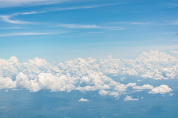 White clouds floating in bright blue sky from a plane's window v