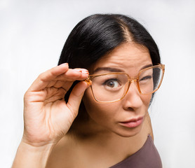 Portrait of beautiful Korean or Asian woman in glasses in studio. Brunette lady posing for photographer over white background.