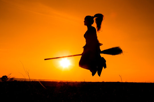 Silhouette of young witch flying on the broomstick