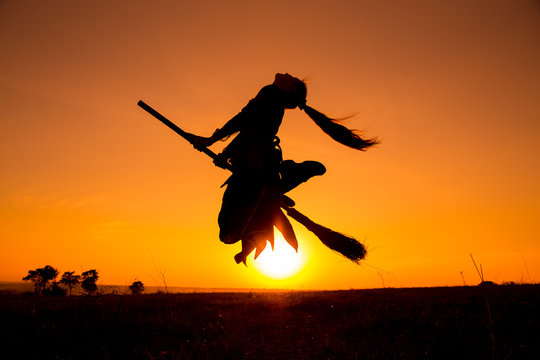 Silhouette of young witch flying on the broomstick