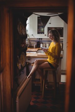 Beautiful woman using mobile phone in kitchen