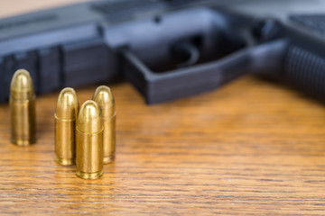 Close up view of bullets and handgun. Shallow depth of field. Pistol out of focus.