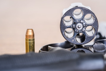 Obraz premium Close up view of bullet and handgun. Shallow depth of field. Focus on a bullet. Vertical view.