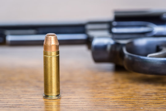Close up view of bullet and handgun. Shallow depth of field. Pistol out of focus. Vertical view.