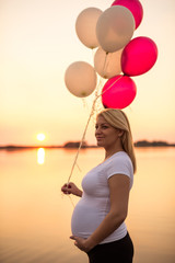 Pregnant woman holding balloons