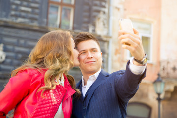 young couple dressed in autumn clothes make selfie on background solar city