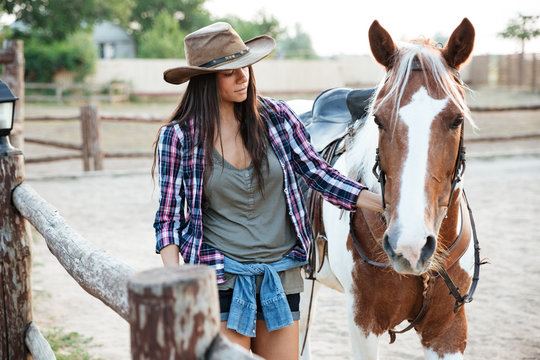 Woman cowgirl walking with her horse on ranch
