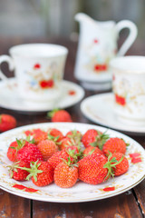 Mature, appetizing strawberries scattered on the white plate.