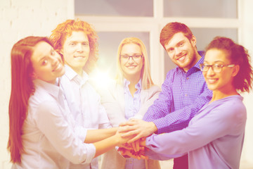 team with hands on top of each other in office