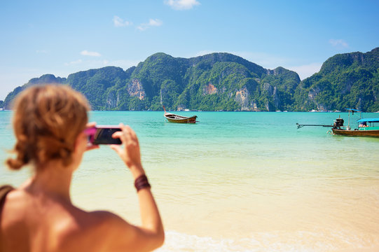 Travel lifestyle. Female tourist taking photo of beautiful lagoon on smartphone.