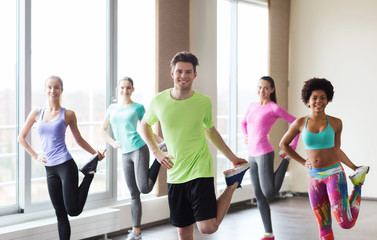 group of smiling people exercising in gym