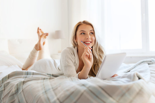 happy young woman with notebook in bed at home