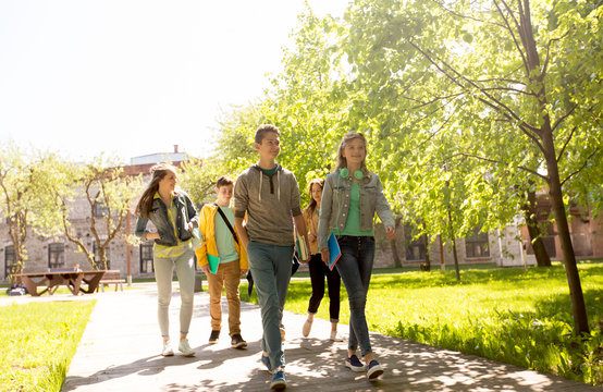 group of happy teenage students walking outdoors