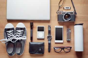 Outfit of modern traveler, student, woman or guy. Overhead of essentials on wooden background:...