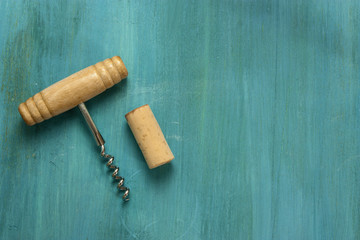 Retro corkscrew and cork on turquoise with copyspace