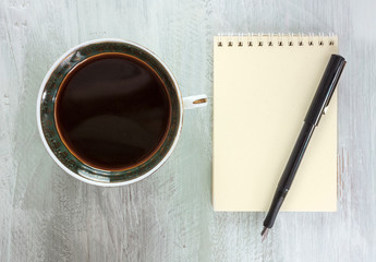 Retro cup of coffee with ink pen on notepad