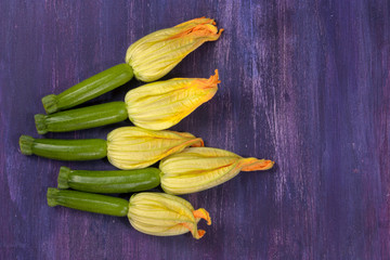 Zucchini flowers, shot from above on purple background