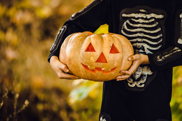 Hands Boy in halloween masquerade costume ih light from pumpkin head.
