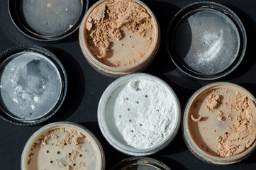 Horizontal background with variety of mineral powders for matt make-up on black surface