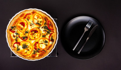 Homemade cheesy egg Quiche for Brunch with spinach and pepper on a brown wooden background.