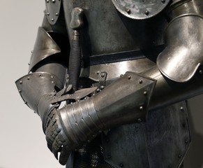 DETALLE DE LOS GUANTES DE METAL DE UNA ARMADURA MEDIEVAL SUJETANDO UNA ESPADA