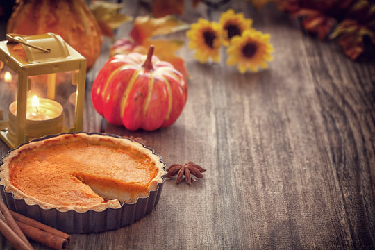 Thanksgiving pumpkin pie with pumpkin and lantern on wooden background 