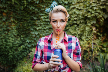 Smiling woman drinking soda with straw outdoors