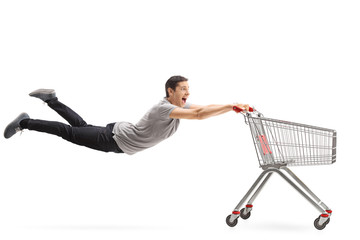 Young guy being pulled by an empty shopping cart