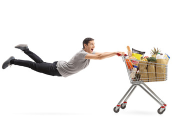 Man being pulled by a shopping cart full of groceries © Ljupco Smokovski