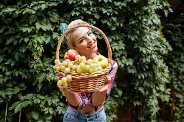 Smiling pin-up girl giving you basket of fresh fruits