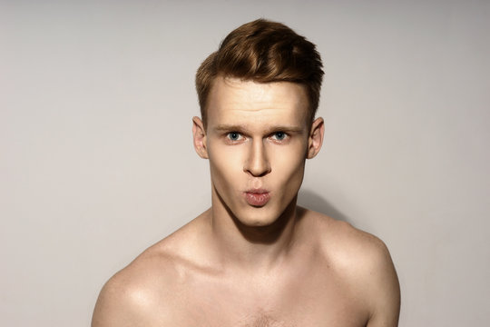 Studio fashion style closeup face portrait of young emotional man giving a kiss