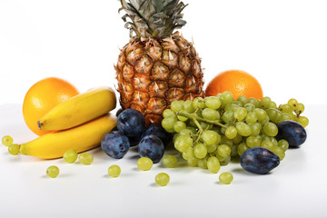 Fruits on a white background. Bananas, plums, pineapple, grapes