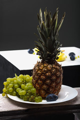 Fruits on the wooden table. Bananas, plums, pineapple, grapes on