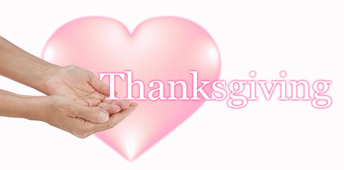 Share your Love at Thanksgiving - female hands in cupped gesture with the word THANKSGIVING to the right with a big soft focus pink heart in the background
