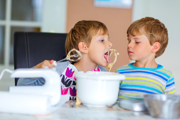 Two kid boys baking cake in domestic kitchen