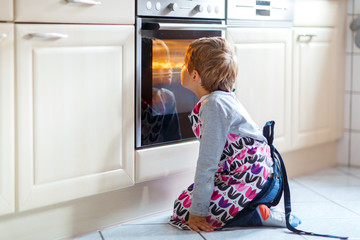 Boy looking at muffins in oven