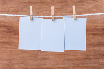 empty three white photo frames hanging with clothespins on woode