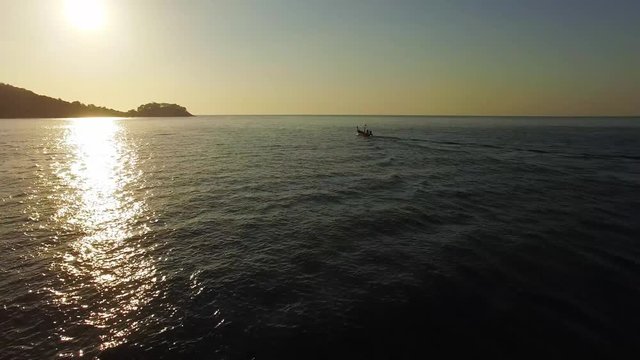 A small fishing boat alone in the sea at sunset. Aerial video