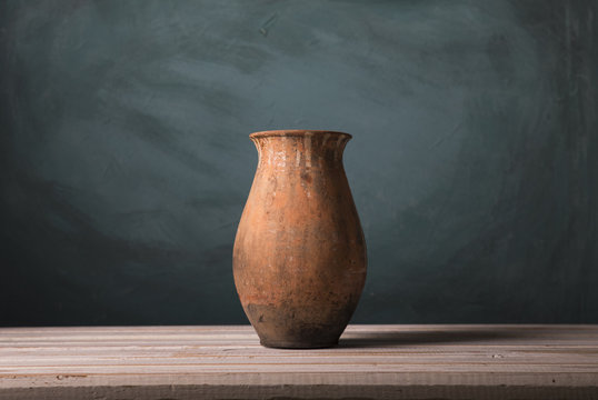 Red ornamental clay pot/Pottery vase made of clay and painted in red against a green background