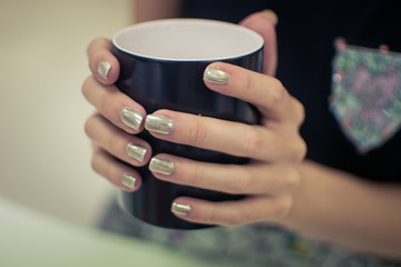 Girl's hands holding a cup of coffee. nails, manicure
