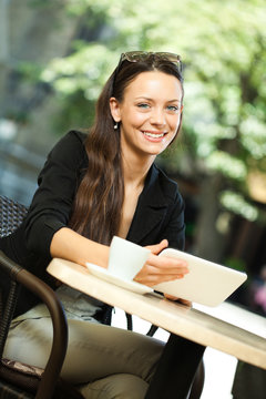 Young woman is using digital tablet in a cafe.