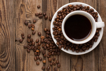 Coffee cup and coffee beans on wooden background.