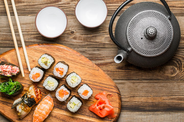 Sushi, rolls, teapot and cups on table