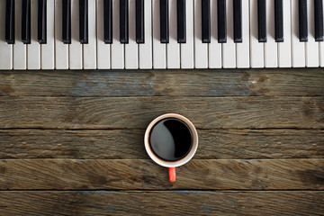 Piano keys and red coffee mug on wood table for composer concept. © bongkarn